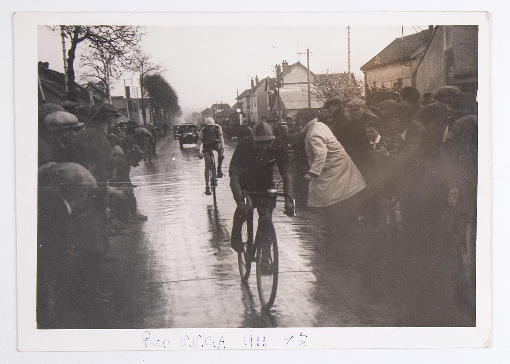 38 Fi 15 -  Prix de l'Union Vélo Club de l'Aube (U.V.C.A). Deux coureurs cyclistes sous la pluie, au milieu des spectateurs. Lieu non identifié.